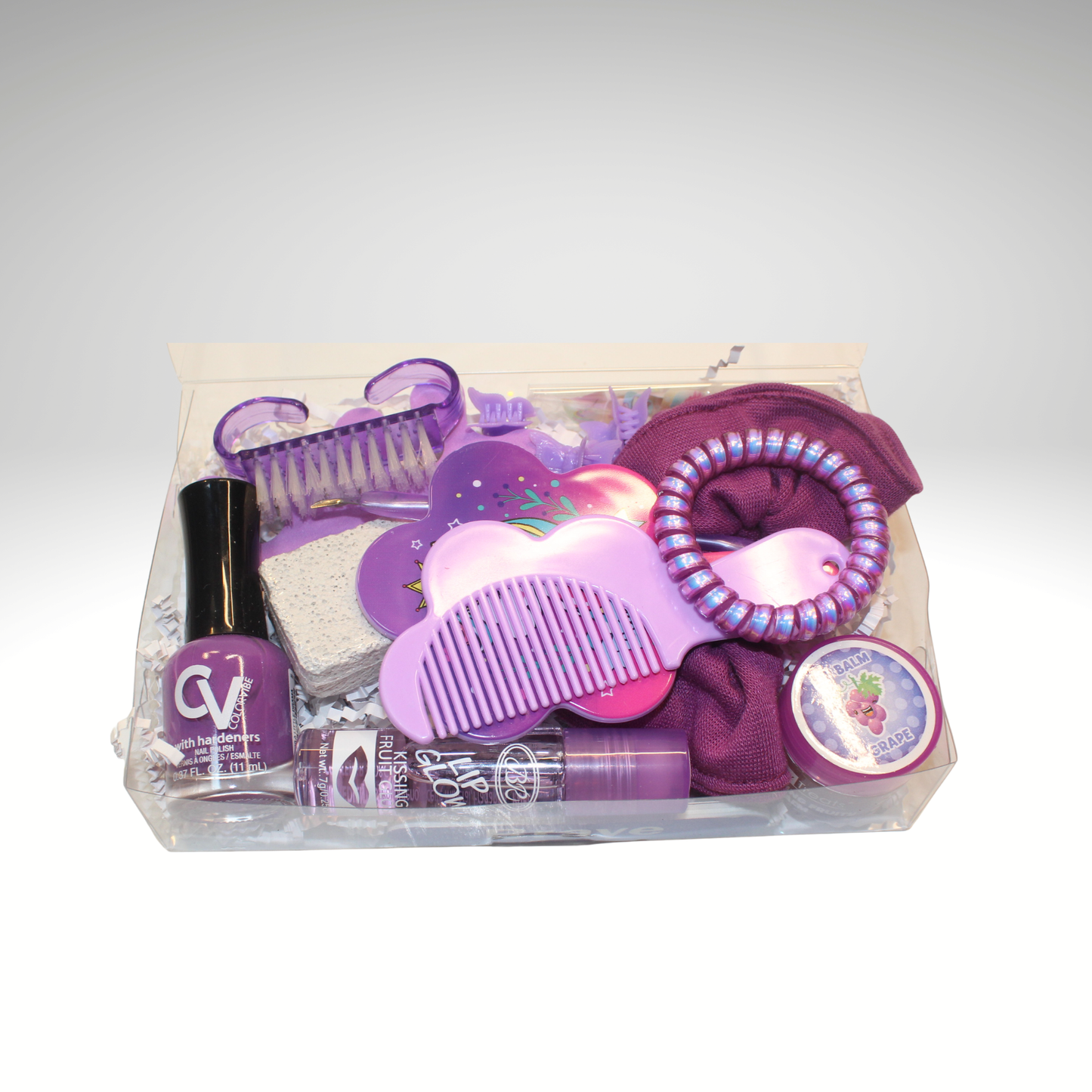 Purple beauty product set with nail polish, brush, and other items in a clear bag on a white background