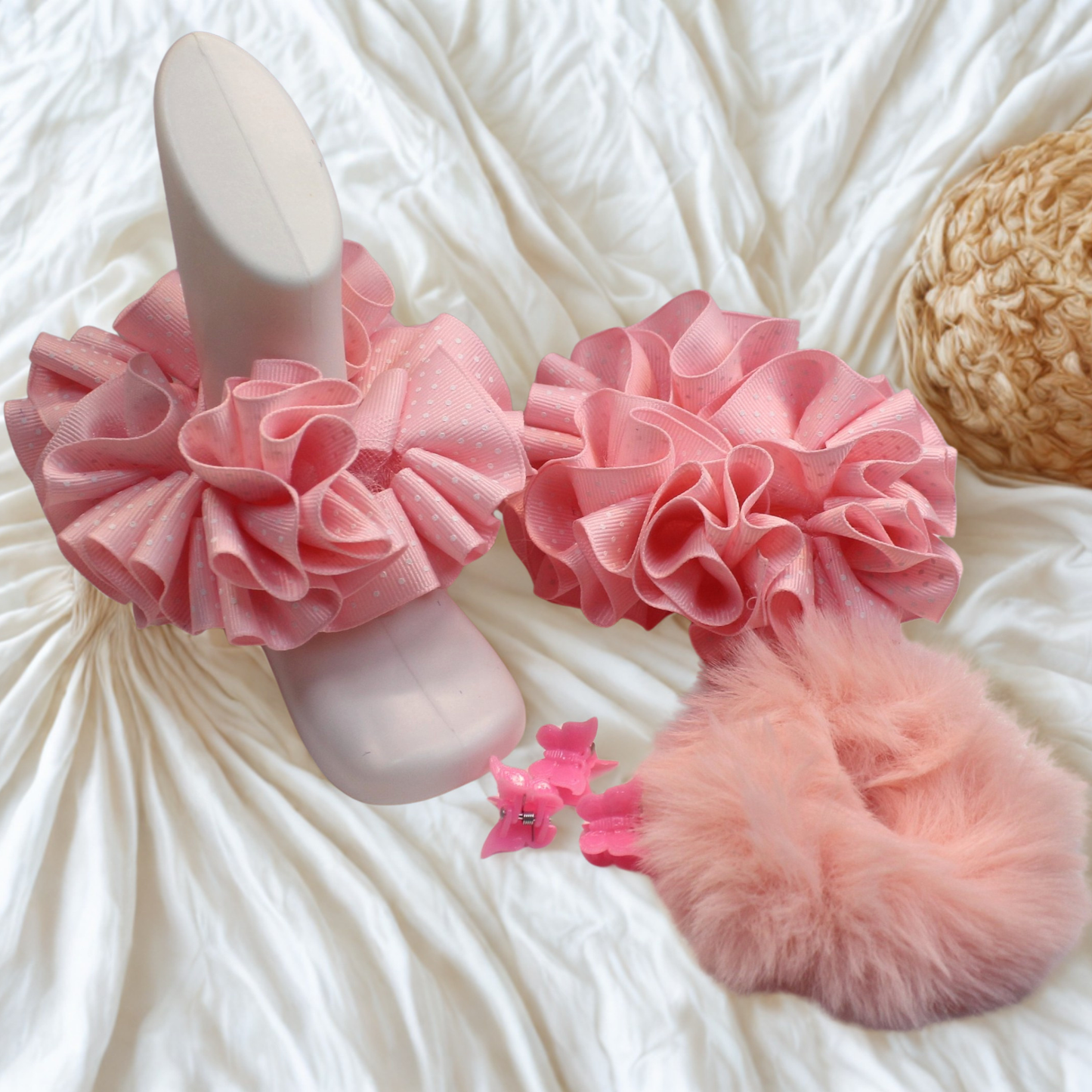 Pink ruffled slippers with fluffy pom-pom on a textured white surface