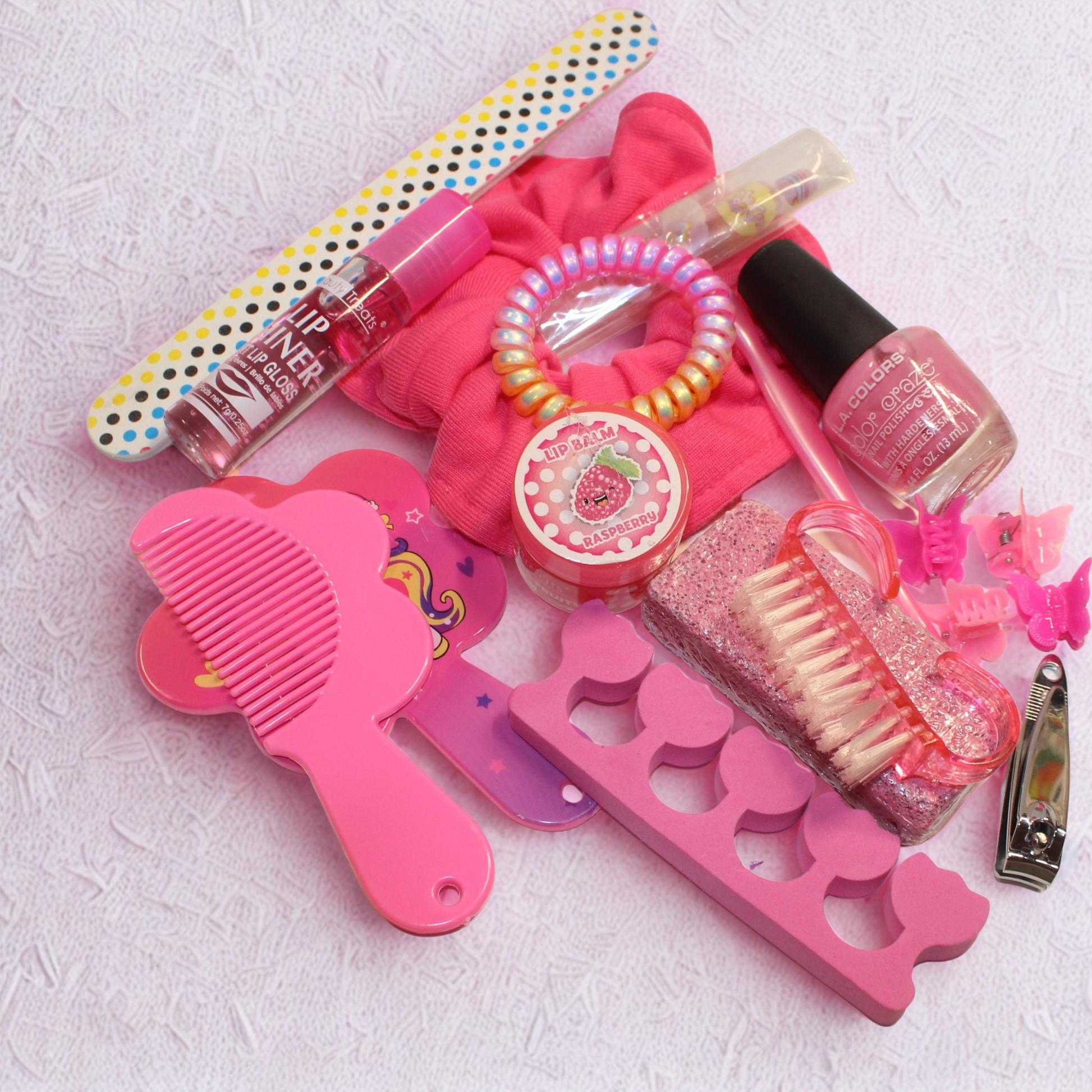 Collection of pink beauty and hair care products on a textured white surface