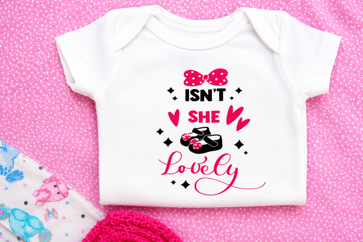 White baby onesie with pink and black text on a pink polka dot background